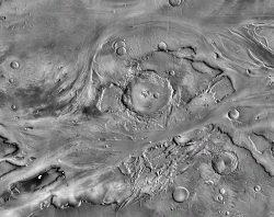 The floods that carves Kasei Valles flowed from left to right through this image. The large impact crater on the mesa (center) is Sharonov, 100 km (62 mi) wide. Channels swerve around the mesa, which stands 2,000 meters (6,600 feet) higher than the channel beds flanking it. Evidence of flowing water lies almost everywhere in the image. (NASA/JPL-Caltech/Arizona State University)